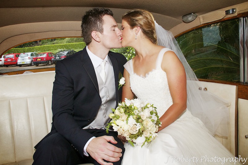 Couple kissing in back of the bridal car - wedding photography sydney